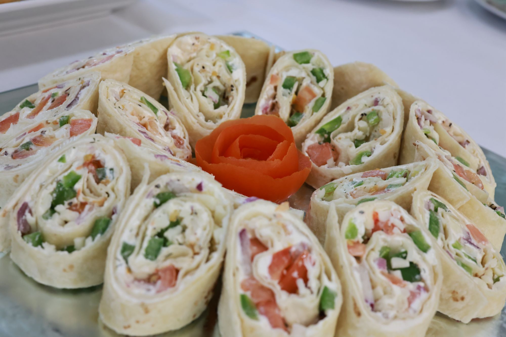 This is a platter with a rose surrounded by sandwich wraps
